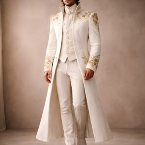 May include: A cream-coloured formal suit with gold embroidery. The outfit includes a long coat, waistcoat, trousers, and boots. The coat features elaborate gold detailing on the shoulders and sleeves. A sophisticated ensemble for formal events.