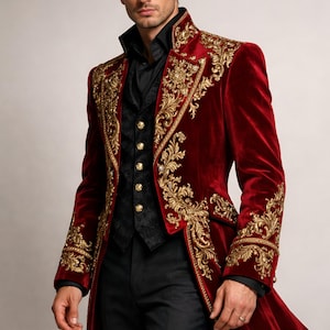 Puede incluir: Un abrigo de terciopelo rojo con bordados dorados. El abrigo presenta detalles dorados ornamentados en las solapas, los puños y la espalda. El atuendo incluye un chaleco negro y pantalones negros. El abrigo es de estilo largo y formal.