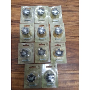 May include: Eleven individual silver-toned metal drawer pulls shaped like small teacups, each packaged in a clear plastic blister pack on a cardboard backing labeled Drawer Pull, including a small metal mounting screw for each unit.