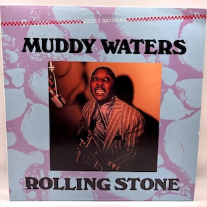 May include: A vintage vinyl record album cover featuring Muddy Waters. The cover has a blue and purple background with the words "MUDDY WATERS" and "ROLLING STONE" in bold black letters. A photograph of Muddy Waters is in the center.