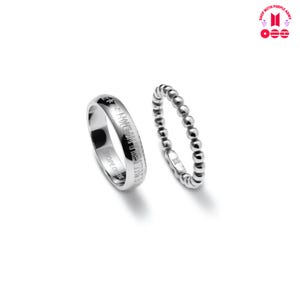 May include: Two silver rings on a white background. One ring has engraved text, and the other is a beaded design. The rings are likely made of sterling silver or a similar metal. The rings are part of a jewelry collection.