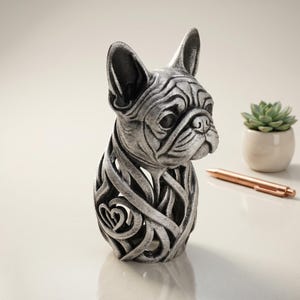May include: A silver-toned French bulldog figurine featuring a detailed, openwork lattice body design with a small heart shape integrated into the lower section. The sculpture has a metallic finish with dark shading to highlight the facial features.
