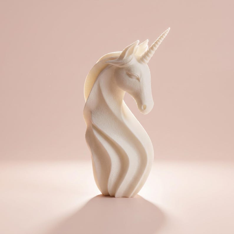 May include: A cream-colored unicorn figurine with a spiraling body and a detailed horn. The sculpture has a flowing mane and is set against a soft pink background, creating a whimsical and elegant aesthetic.