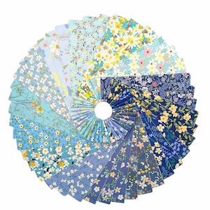 May include: A circular display of fabric squares in shades of blue, each with a different floral design. The patterns include daisies and other small flowers. The fabric pieces are arranged in a spiral, showcasing a variety of quilting fabrics.