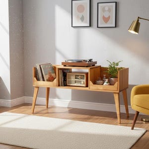 Puede incluir: Consola de tocadiscos de estilo moderno de mediados de siglo en madera clara. La consola cuenta con un tocadiscos, una radio vintage y espacio para guardar discos de vinilo. Una lámpara de pie dorada y un sillón amarillo completan la decoración.