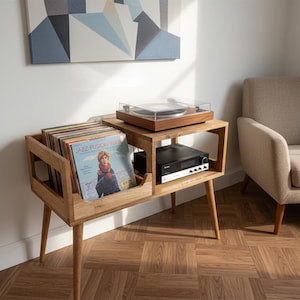 Może przedstawiać: Drewniany stojak na gramofon z wbudowaną przegrodą do przechowywania płyt winylowych. Stojak ma gramofon na górze i odbiornik stereo na półce poniżej. Widoczny jest stos płyt winylowych.