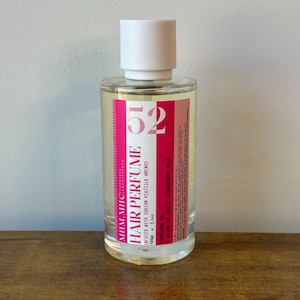 May include: A white ceramic mug with a black handle and the text "But First, Coffee" in a bold, black font. The mug is set against a blurred background, suggesting a cozy setting.