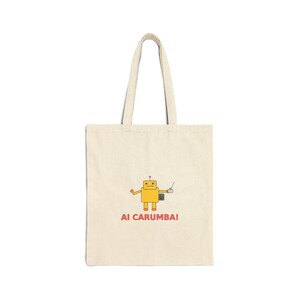 Puede incluir: Un bolso tote de color crema con un gráfico de robot amarillo y el texto "AI CARUMBA!". El robot tiene un cuerpo en forma de caja, una cabeza cuadrada y brazos extendidos. El bolso tiene dos asas largas.