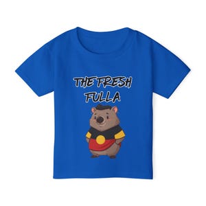 May include: Royal blue t-shirt featuring the text "THE FRESH FULLA" above an illustration of a wombat wearing a shirt with Aboriginal Australian flag colors. The wombat is brown with a black hat.