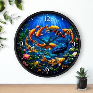 May include: Black-framed wall clock featuring a vibrant underwater scene with koi fish in shades of orange, yellow, and black. The clock face has a blue background with numbers at the 12, 3, 6, and 9 o'clock positions. The clock hands are black.
