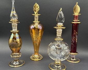 Conjunto de 4 frascos de perfume vintage em vidro com detalhes dourados, nas cores âmbar, transparente e vermelho.