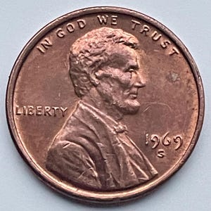 Op de afbeelding: Een koperkleurige 1969 S Lincoln penny. De voorzijde toont een profiel van Abraham Lincoln, het woord "LIBERTY" en de zin "IN GOD WE TRUST". Het jaartal "1969" en het muntteken "S" zijn ook zichtbaar.