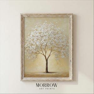 May include: A framed art print depicting a tree in full bloom with white flowers. The tree has a brown trunk and branches, set against a light yellow backdrop. The frame is a light beige colour. The text "MORROW ART PRINTS" is at the bottom.