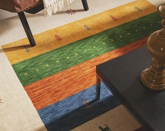 May include: A rectangular area rug featuring a cream-colored base with horizontal bands in mustard yellow, forest green, burnt orange, and navy blue. The rug is decorated with small, scattered embroidered motifs including trees and animal shapes.