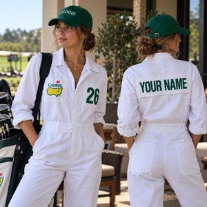 May include: A white long-sleeve jumpsuit featuring a green CADDIE logo with a flag on the chest, the number 26, and a green cap with CADDIE text. The back displays the text YOUR NAME in green on a white patch, paired with a green baseball cap.