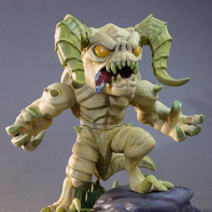 May include: A detailed figurine of a monster with a menacing expression. The creature has yellow eyes, sharp teeth, and horns. Its skin is a pale green with darker green accents. It is posed on a rock base.