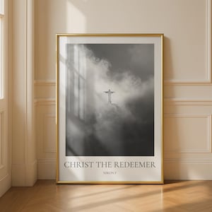 Könnte beinhalten: Ein gerahmter Schwarz-Weiß-Druck mit der Christusstatue in Rio de Janeiro, Brasilien, die aus einem bewölkten Himmel auftaucht. Der Druck hat einen goldenen Rahmen und den Text "CHRIST THE REDEEMER" und "NIKON F" am unteren Rand.