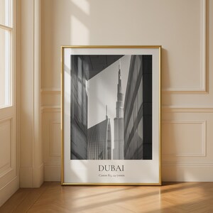 Könnte beinhalten: Gerahmtes Schwarz-Weiß-Foto der Skyline von Dubai mit dem Burj Khalifa. Das Bild ist in einem goldenen Rahmen eingefasst und zeigt den Stadtnamen "DUBAI" am unteren Rand sowie Kameradetails.