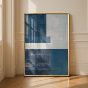 May include: A rectangular wall art print featuring an abstract composition of geometric blocks in shades of deep navy blue, slate blue, and off-white. The artwork is encased in a thin, metallic gold frame with a smooth, reflective finish.