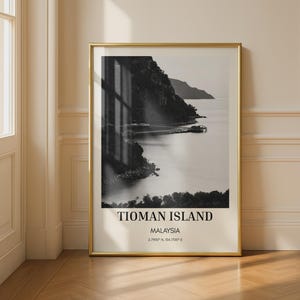 Könnte beinhalten: Ein vertikaler gerahmter Wandkunstdruck mit einer schwarz-weißen Landschaftsaufnahme von Tioman Island, Malaysia. Der Druck enthält den Text TIOMAN ISLAND, MALAYSIA sowie die Koordinaten 2.7900 N, 104.1700 E in einer klaren, schwarzen Serifenschrift.