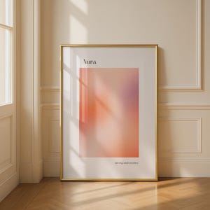 May include: A framed art print with a gold frame. The print displays a colour gradient, shifting from orange to purple. The word "Aura" is at the top, and "strong and creative" is at the bottom.