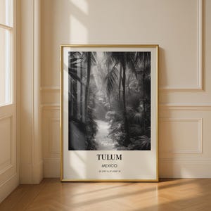 Puede incluir: Fotografía en blanco y negro enmarcada de un sendero en la jungla con palmeras. La fotografía está en un marco dorado y tiene el texto "TULUM MEXICO" en la parte inferior, junto con las coordenadas 20.210° N, 87.429° W.