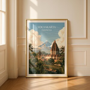 May include: A framed travel poster featuring a landscape illustration of Yogyakarta, Indonesia. The artwork depicts ancient stone temple structures surrounded by lush green trees and palm trees, with a large volcanic mountain and clouds in the background.
