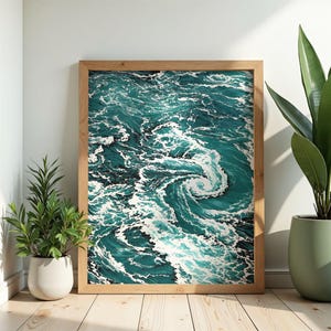 Può includere: Una stampa artistica incorniciata con una rappresentazione astratta di onde oceaniche nei toni del verde acqua e bianco. L'opera d'arte è esposta in una cornice di legno naturale e appoggiata a una parete bianca. Piante in vaso sono posizionate sul pavimento.