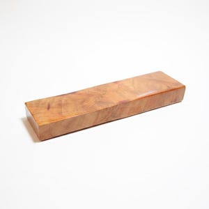 May include: A rectangular wooden block with a polished, light brown finish. The wood grain is visible, creating a natural, textured appearance. The block is likely a craft supply or a component for woodworking projects.