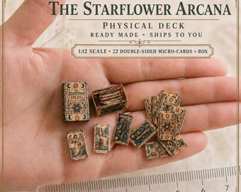 May include: A 1:12 scale miniature tarot deck titled The Starflower Arcana, featuring 22 double-sided micro-cards and a small box. The cards display intricate celestial and floral illustrations in muted tones, shown with a ruler for scale.