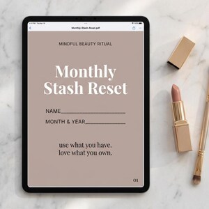 May include: A tablet displaying a digital document titled Monthly Stash Reset with the text Mindful Beauty Ritual and use what you have. love what you own. The screen features fields for name, month, and year. A lipstick and makeup brush are nearby.