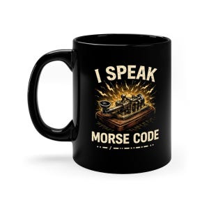 May include: Black ceramic mug with a white handle. The mug features the text "I SPEAK MORSE CODE" with an illustration of a vintage telegraph machine. The design includes Morse code symbols.