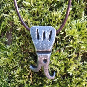 May include: A white ceramic mug with a black handle and the text "But First, Coffee" in a bold, black font. The mug is set against a blurred background. The mug appears to be approximately 10 cm tall.