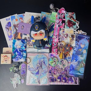 May include: A collection of anime-themed merchandise, including plush toys, keychains, stickers, and lanyards. The items feature various characters in vibrant colors, with a focus on detailed artwork and designs. The assortment includes a plush doll with a black hat and red eyes.