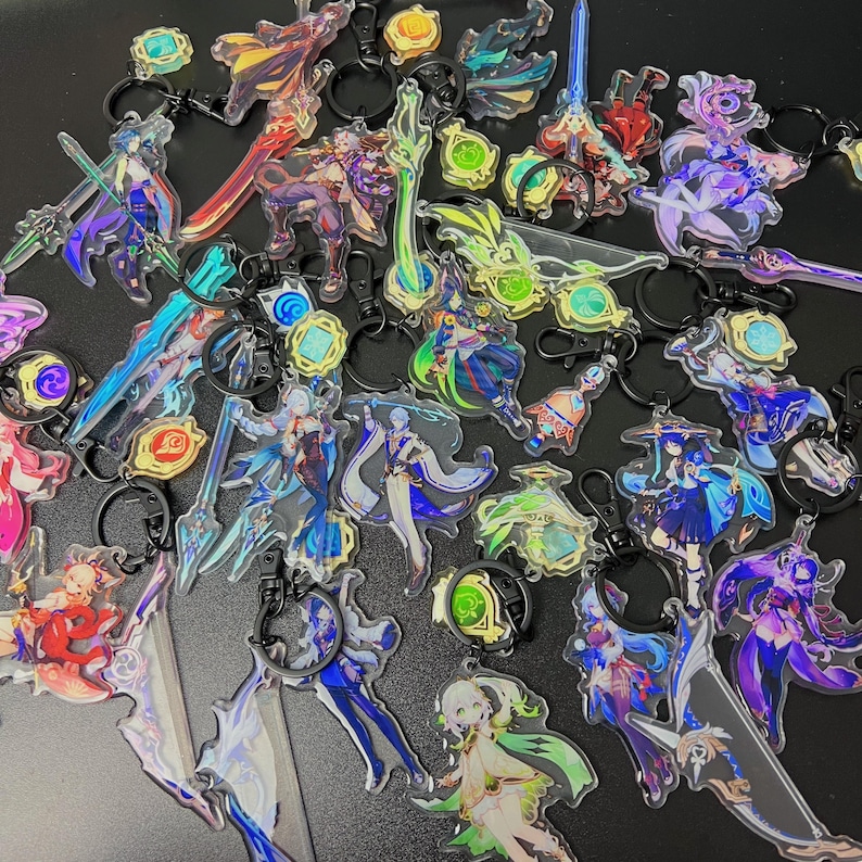May include: A collection of acrylic keychains featuring various anime-style characters and weapons. The keychains have black metal rings and clasps. The designs include figures in shades of blue, purple, green, and red, with intricate details and transparent elements.