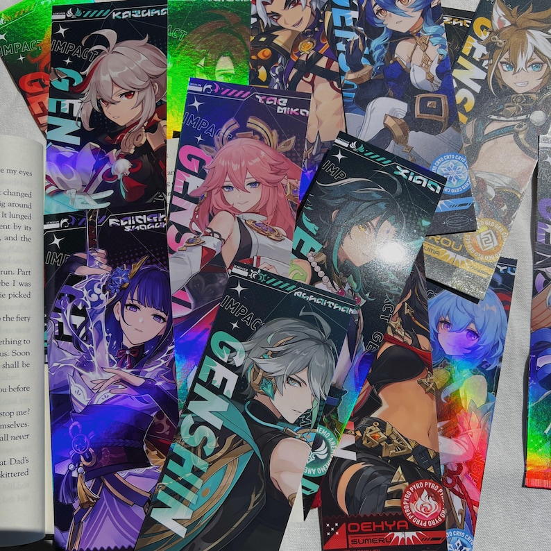 May include: A collection of colorful Genshin Impact character bookmarks. Each bookmark features a different anime-style character with vibrant colors and holographic accents. The word "GENSHIN" is prominently displayed on several bookmarks.