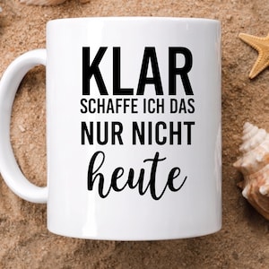 May include: A white ceramic mug featuring the black printed text KLAR SCHAFFE ICH DAS NUR NICHT heute. The mug has a smooth cylindrical body with a curved handle on the left side, designed for holding hot or cold beverages in a standard capacity.