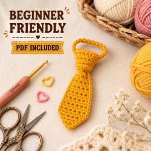 May include: A mustard yellow crocheted necktie with a loop at the top. The image includes text reading BEGINNER FRIENDLY and PDF INCLUDED, a 3.0 mm crochet hook, two small heart-shaped stitch markers, and vintage-style metal scissors.