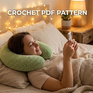 Puede incluir: Una almohada de cuello de ganchillo verde claro está alrededor del cuello de una persona. La persona está acostada en una cama con una manta y almohadas. El texto "CROCHET PDF PATTERN" está en la parte superior de la imagen.