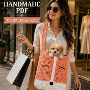 May include: A crochet tote bag designed to look like a fox, featuring a peach-colored body with a white snout, black embroidered eyes, and a black nose. The bag has a long shoulder strap and contains a small, fluffy puppy inside the main compartment.