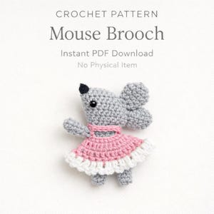 May include: A crocheted mouse brooch in gray, wearing a pink and white dress. The text at the top reads "CROCHET PATTERN Mouse Brooch." Below the title, the text reads "Instant PDF Download No Physical Item."