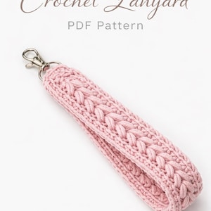 May include: A pink crochet lanyard with a silver-colored clasp. The lanyard is made of a soft, woven material with a braided design. The text "Crochet Lanyard PDF Pattern" is in the upper portion of the image.