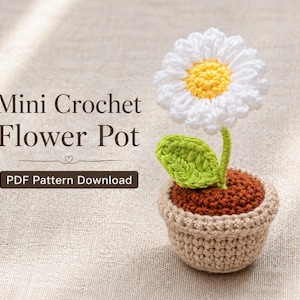 Könnte beinhalten: Ein handgefertigter Mini-Häkelblumentopf mit einer weißen Gänseblümchenblüte mit gelber Mitte, einem grünen Blatt und einem braunen Topf. Der Topf ist beige. Der Text lautet "Mini Crochet Flower Pot" und "PDF Pattern Download".