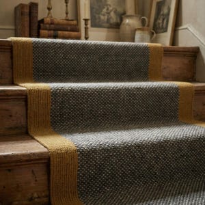May include: A stair runner featuring a textured grey centre with a speckled white pattern, bordered by solid mustard yellow fabric strips on both sides. The runner is installed over wooden stairs, covering the treads and risers in a continuous path.