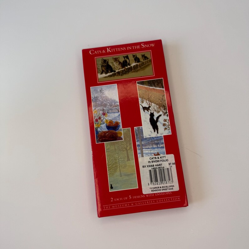May include: A rectangular red folio titled Cats & Kittens in the Snow containing 10 cards and envelopes. The cover features five distinct winter-themed illustrations of cats in snowy landscapes, a barcode, and the Museums & Galleries Collection logo.