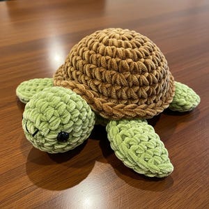 May include: A handmade crochet turtle plushie. The turtle has a brown shell and green head, flippers, and tail. The plushie has a textured, soft appearance. The turtle's eyes are black. The plushie is a cute, handmade item.