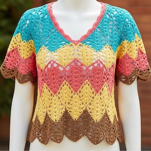 Puede incluir: Un top de ganchillo multicolor con cuello en V. El top presenta un patrón de chevron en tonos turquesa, amarillo, coral y marrón. Las mangas y el escote tienen un borde festoneado. El top se muestra en un maniquí.
