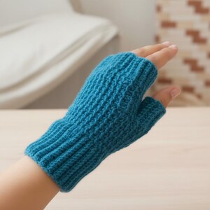 May include: A teal blue fingerless glove made of knitted material. The glove has a ribbed cuff and a textured pattern on the main body. The glove is designed to cover the hand while leaving the fingers exposed.