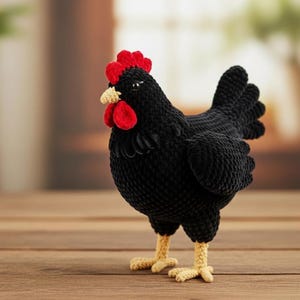 Puede incluir: Una figura de gallina negra hecha a mano con ganchillo, con cresta y barbilla rojas, y patas beige. La gallina está sobre una superficie de madera. El trabajo de ganchillo es detallado y la gallina tiene un aspecto realista.