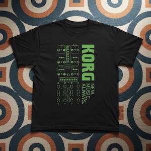 May include: Black t-shirt with a green graphic design. The design includes the word "KORG" in a vertical font, along with the words "NEW. MUSIC. ALWAYS." and a circuit board illustration. The shirt is made of a soft material.